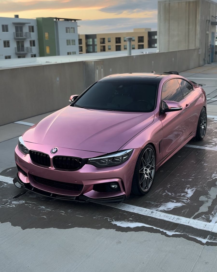Pink BMW coupe with a glossy finish on a Tampa rooftop at sunset